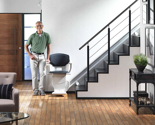 hombre de pie junto a una silla salvaescaleras