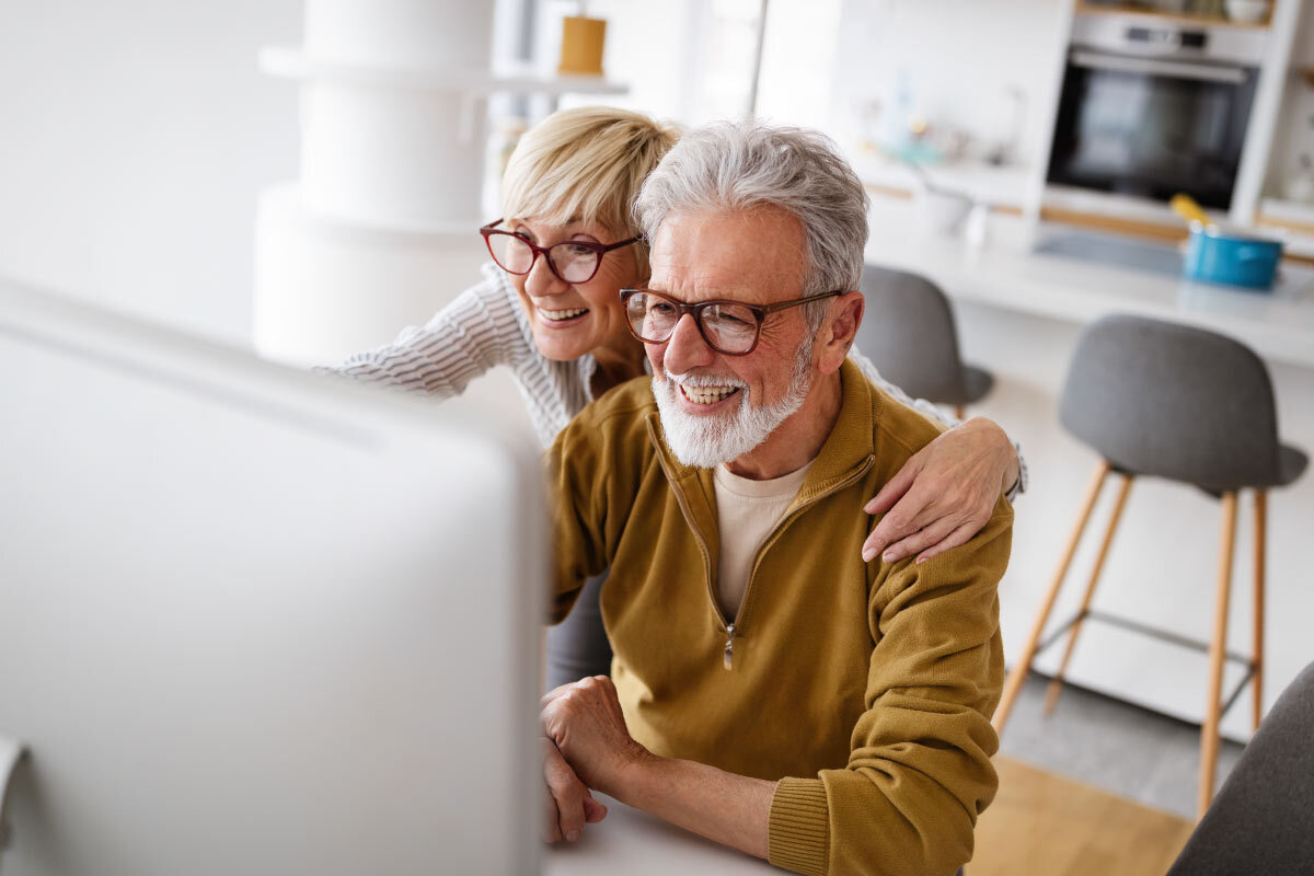 Pareja de ancianos mirando el monitor eligiendo entre silla salvaescaleras o plataforma elevadora